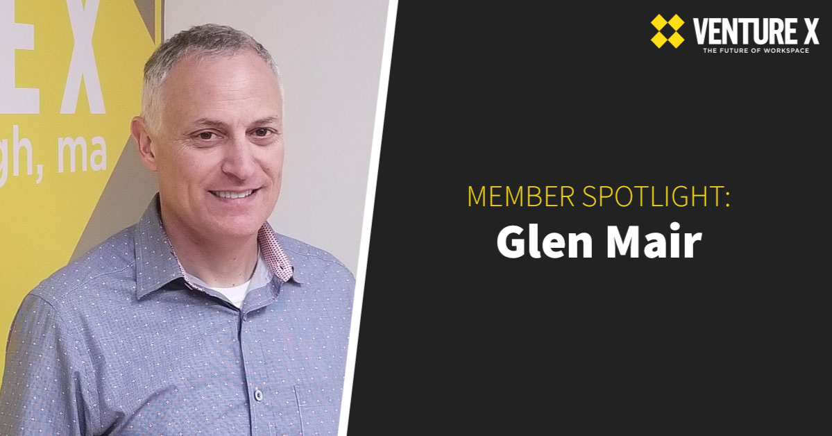 Man standing next to a yellow and white wall with "Venture X" branding; text reads "Member Spotlight: Glen Mair." Celebrating his contribution to our coworking community, Glen appreciates the collaborative energy and creativity found in shared spaces.