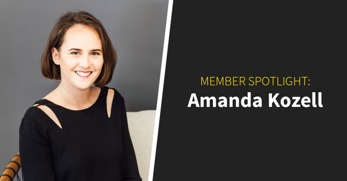 A person with short brown hair sits smiling in a black top, set against a gray backdrop. The text reads, "Member Spotlight: Amanda Kozell," highlighting her role in our vibrant coworking community.