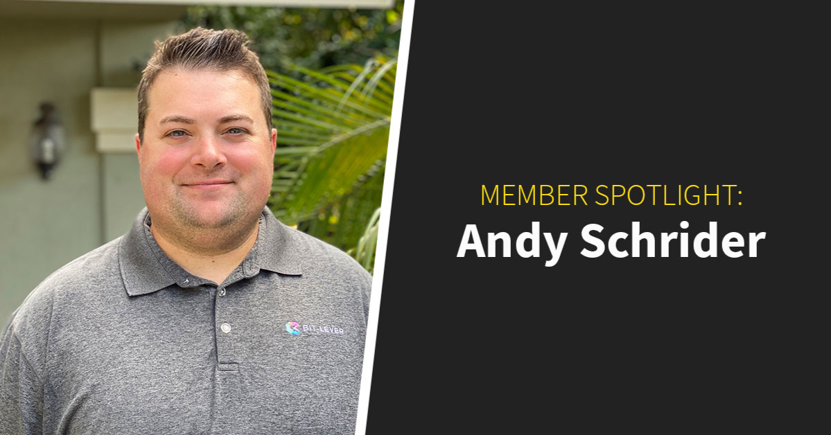 A man in a gray polo stands outdoors beside text reading "Member Spotlight: Andy Schrider," highlighting his role within the coworking community.