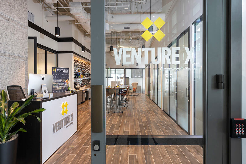 Entrance to venture x coworking space with reception desk and seating area visible through glass doors.