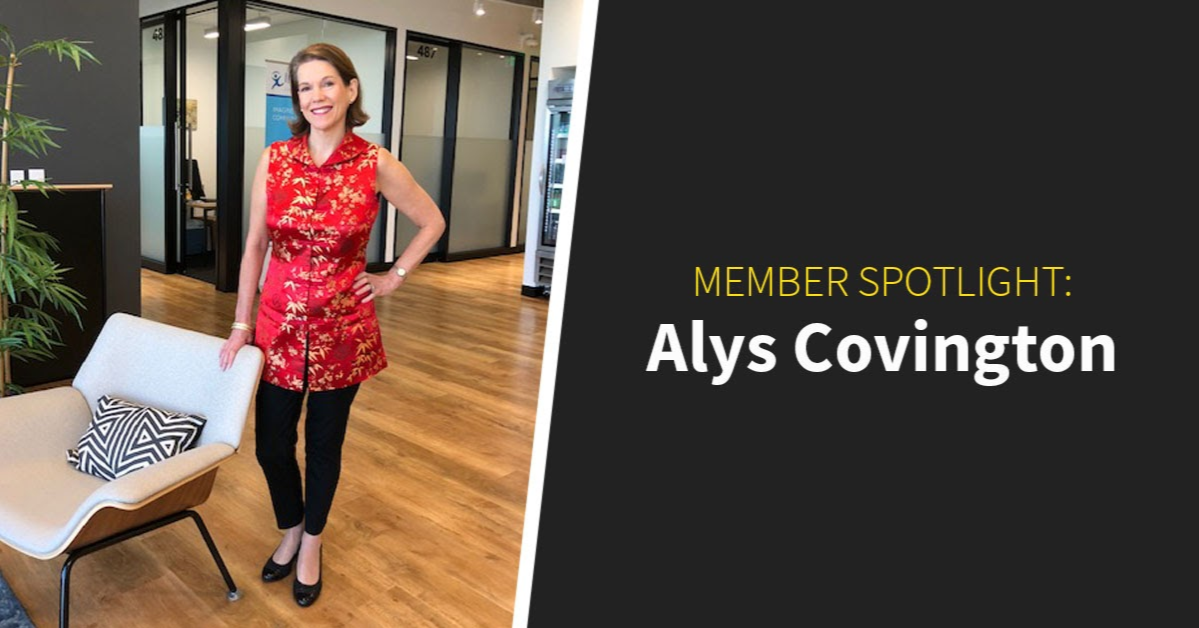 Woman in a red floral top stands next to a chair in a modern coworking community. Text reads: "Member Spotlight: Alys Covington.