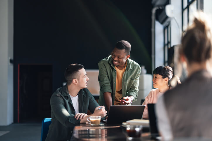 Three people are seated at a table with laptops Three people are seated at a table with laptops