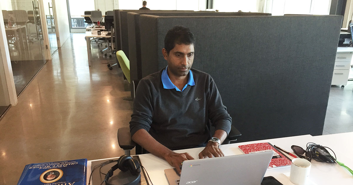 A man is working on a laptop at his desk in a modern virtual office