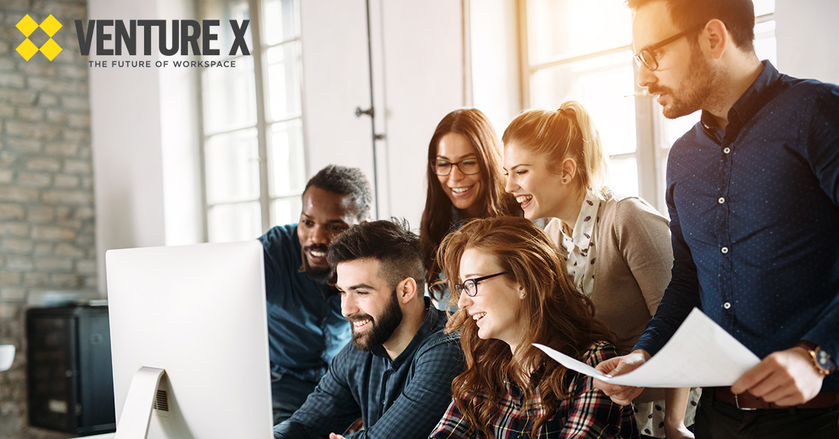 A group of five people gathered around a computer