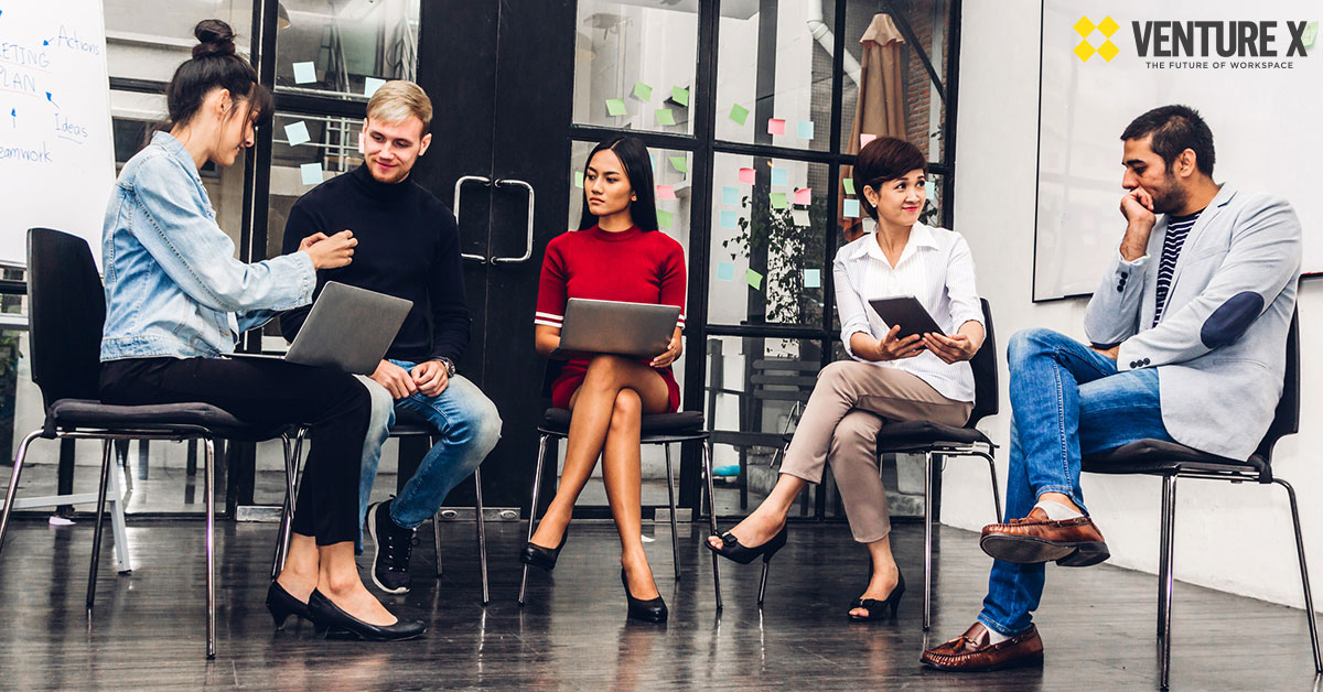 A group of five people engaged in a discussion in a modern coworking space
