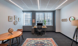 Private office with a colorful rug and large windows in a Venture X location