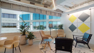 Comfortable chairs in a coworking space at Venture X with large windows, natural light, and brightly colored walls