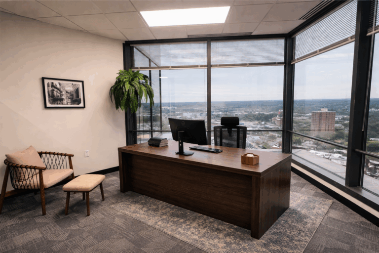 Private executive office with wood desk, guest seating, and floor-to-ceiling windows overlooking downtown Columbia.