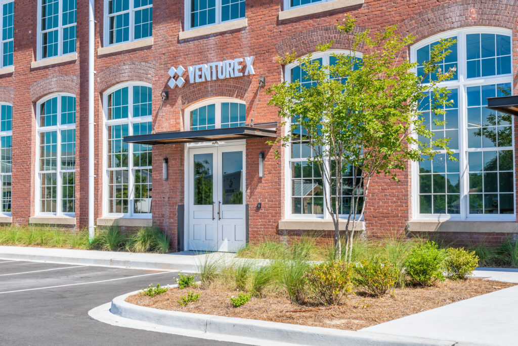 Front door of brick office building with trees and landscaping